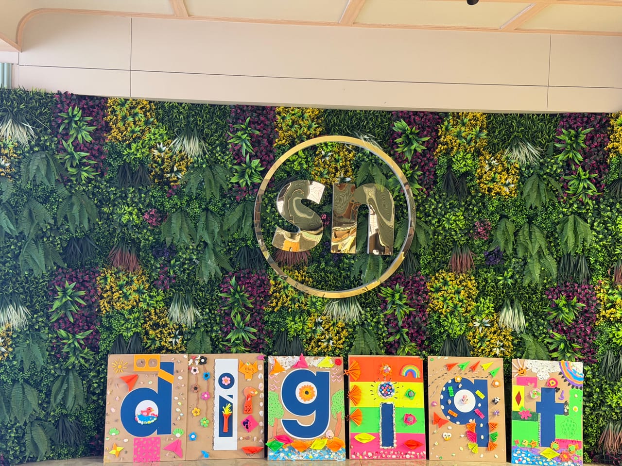 Hand-painted letter boards lined up against the office living-plant wall