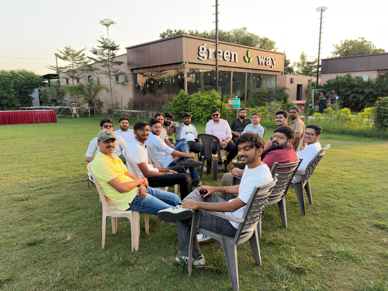 The team sitting in a circle of chairs on the lawn at an evening get-together