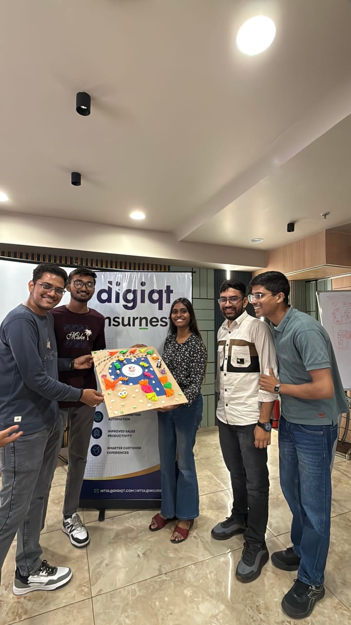 Team members holding up a hand-painted board in front of the office banner